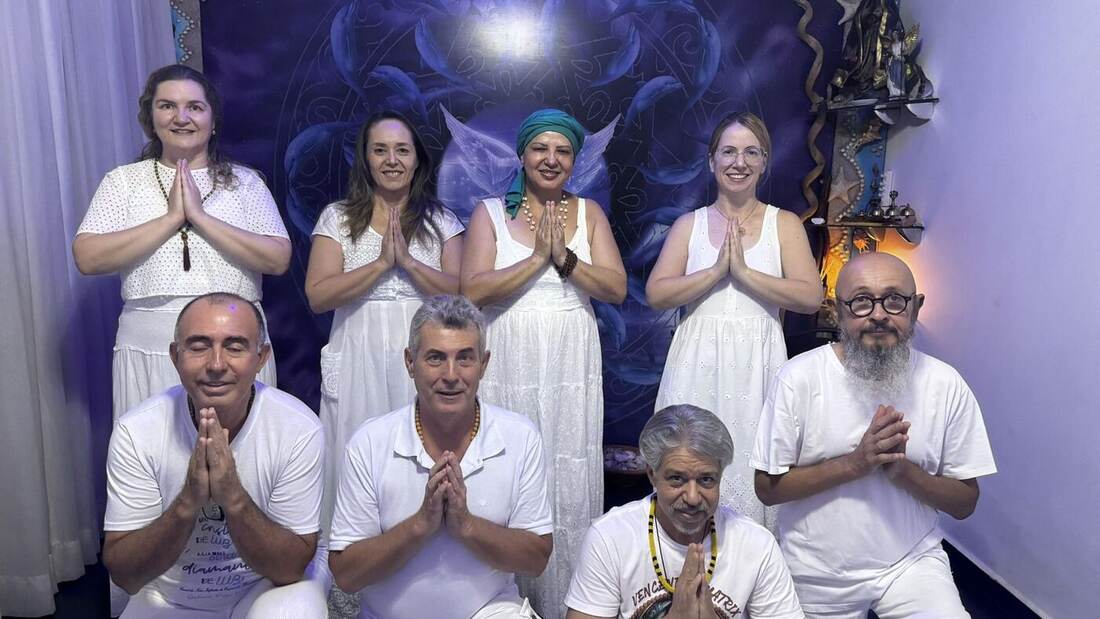 Grupo de pessoas de branco, de mãos unidas em oração